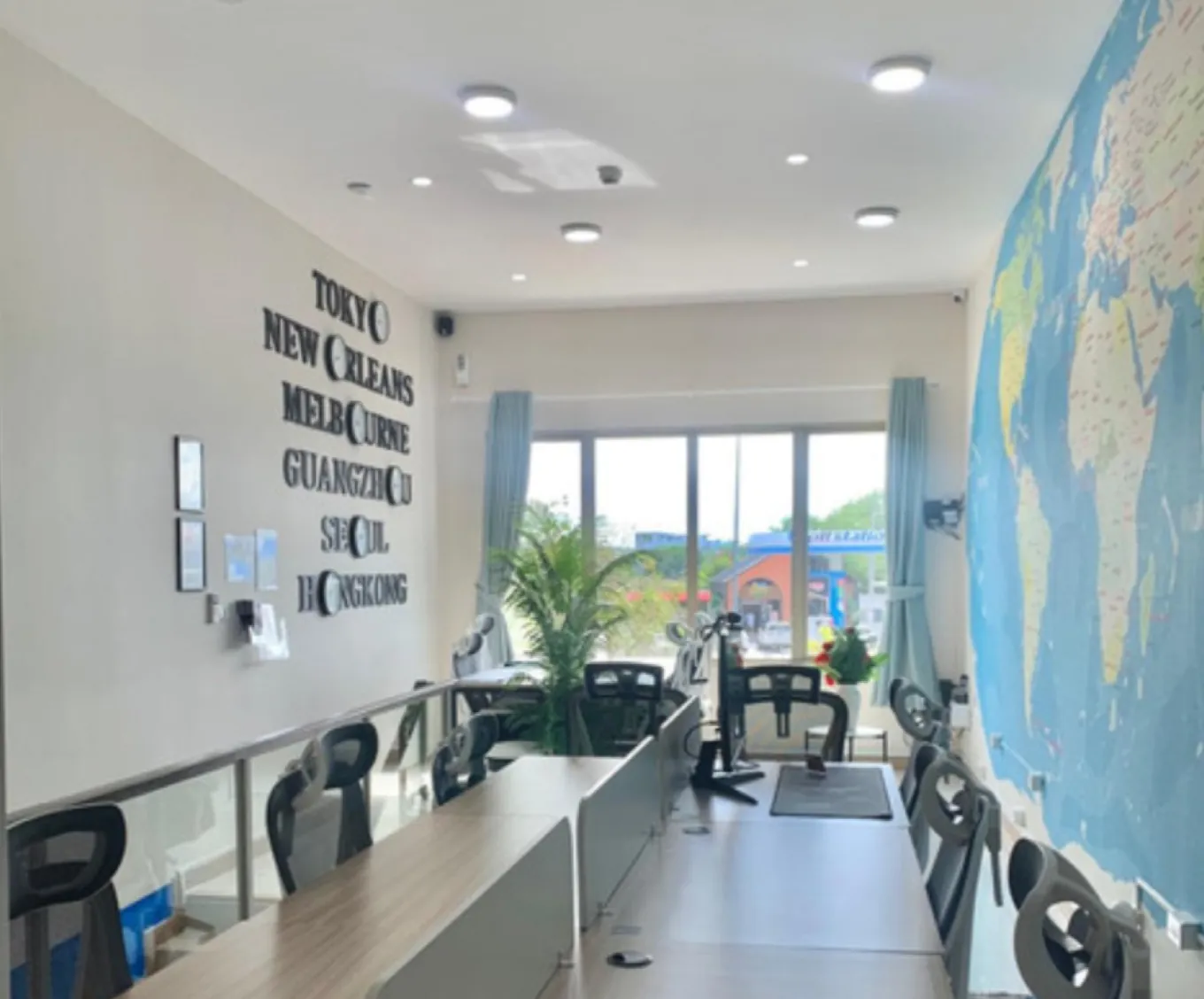 Rows of hot desks along the world map, with the world-clock wall behind